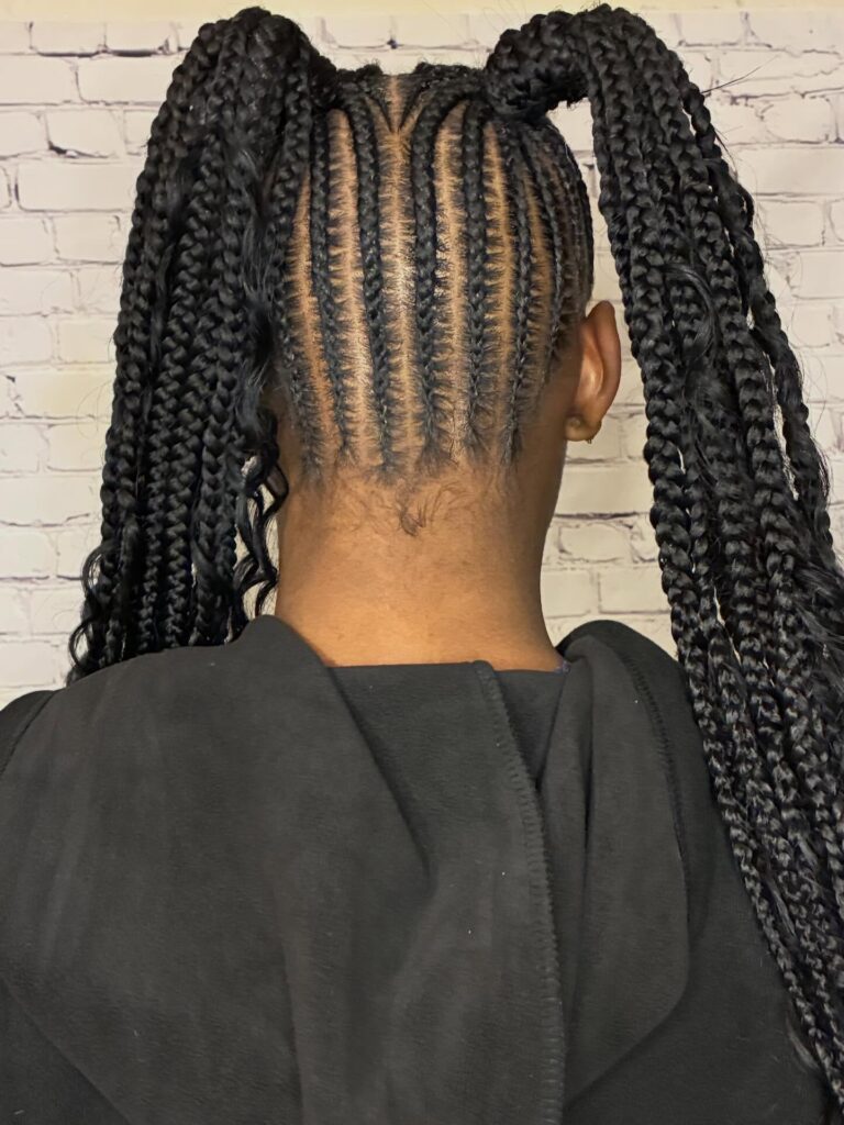 A woman wearing extra long braided pigtails with neat cornrows and thick black braids.