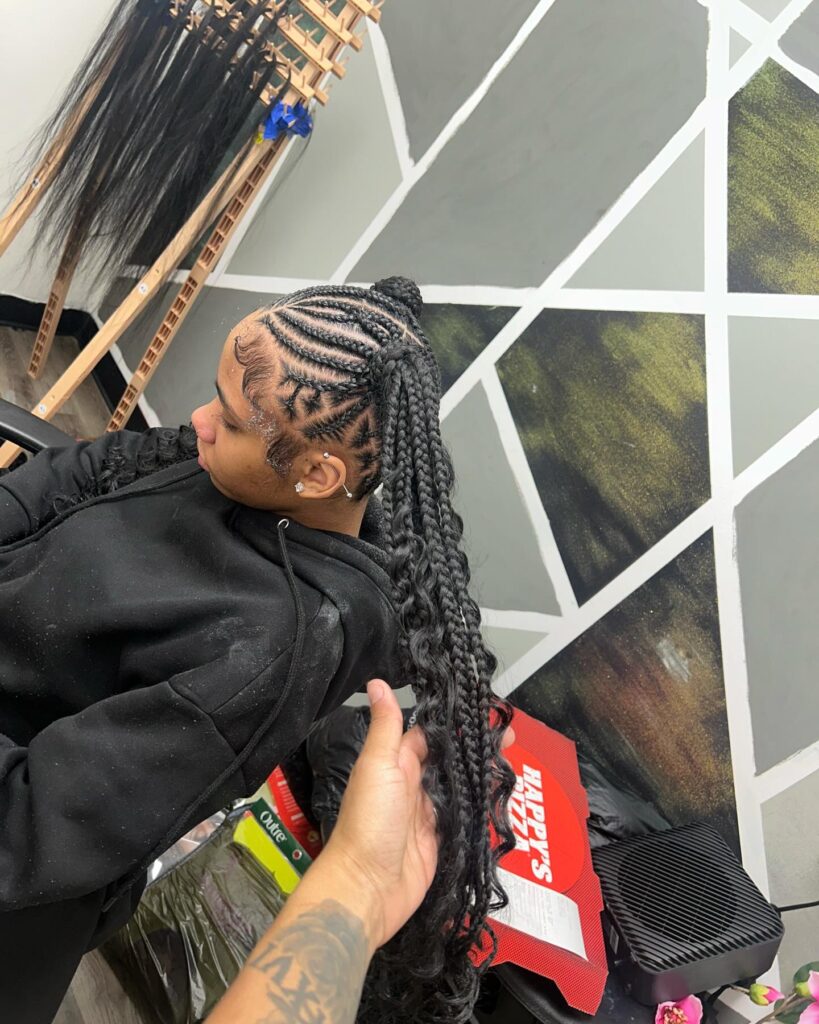 A woman wearing braided ponytails with detailed cornrows and loose curly ends.
