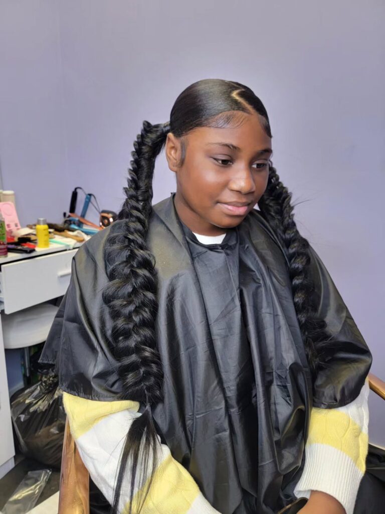 A young girl with sleek twisted bubble ponytails and a side part.
