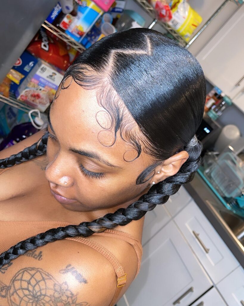 A woman with sleek braided ponytails, swooped baby hairs, and a zigzag part.