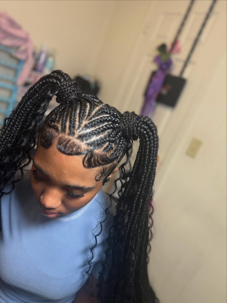A woman with high braided pigtail ponytails featuring neat cornrows and curled ends.