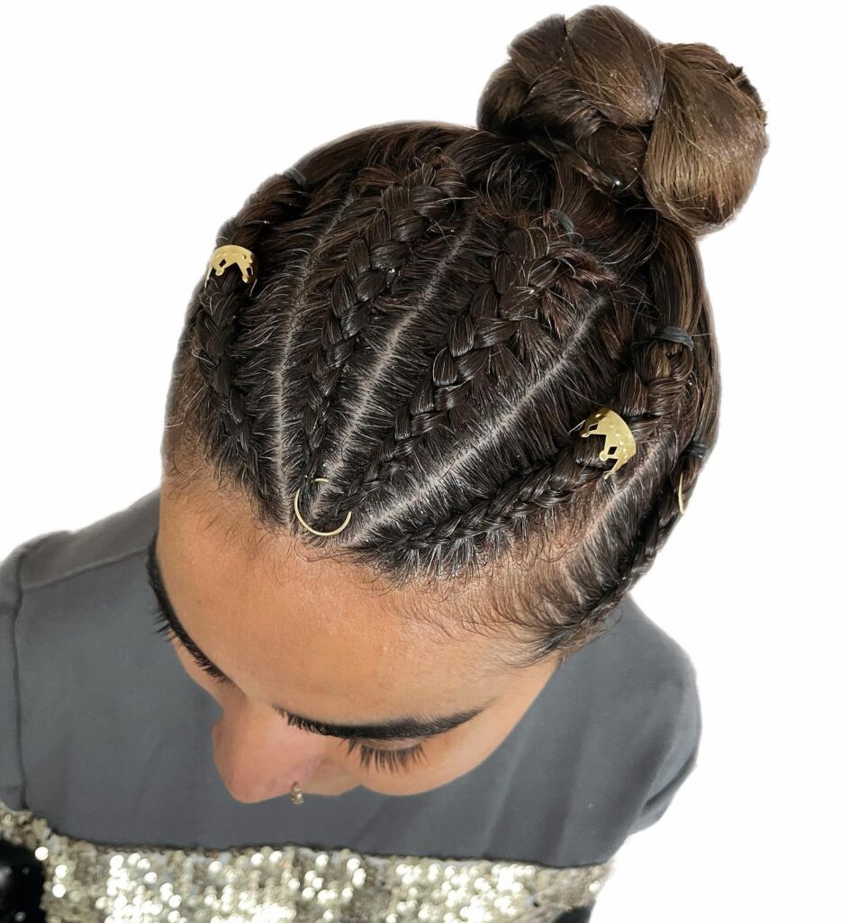 Mini braided hairstyle with a sleek top knot bun and gold hair accessories.