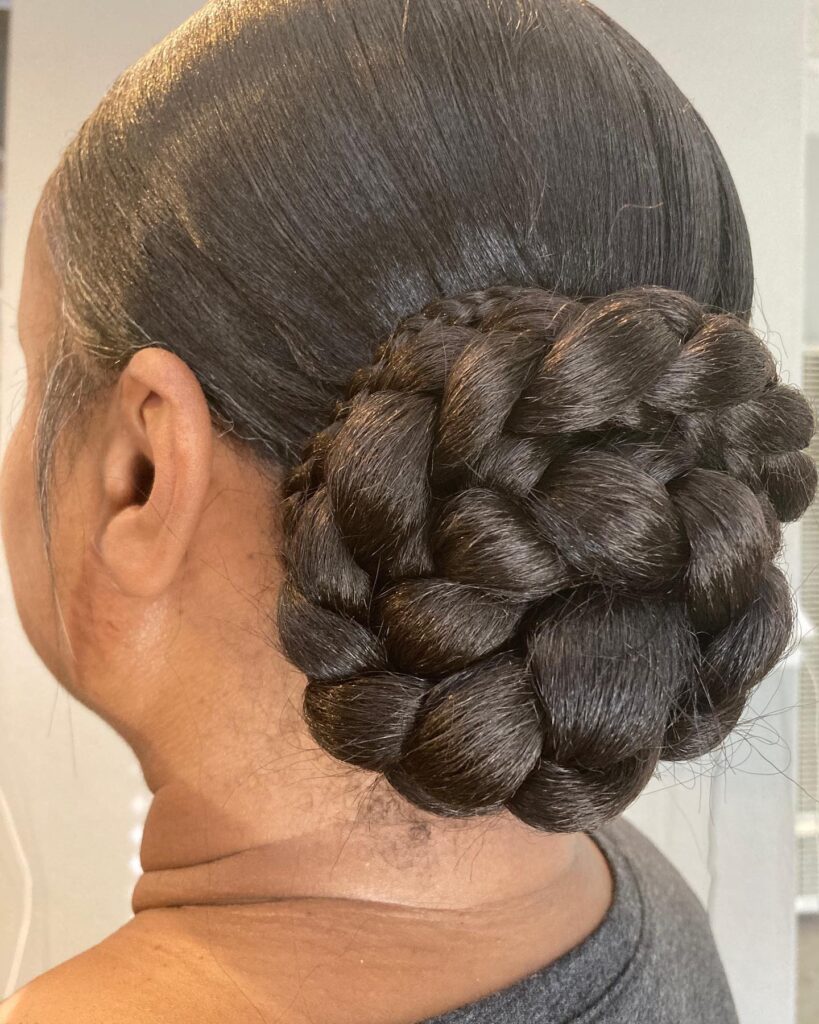 Chunky low braided bun hairstyle with smooth dark brown hair and a rounded woven design.