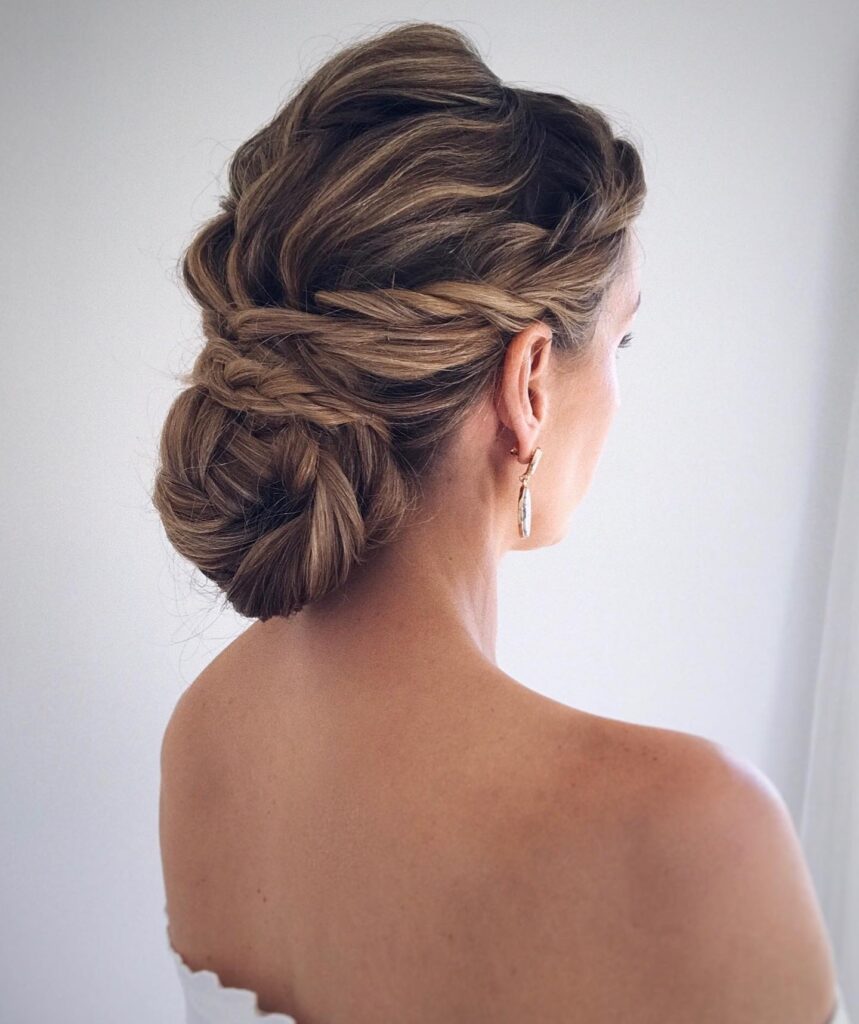 Twisted brunette bridal bun hairstyle with soft braids and textured volume.