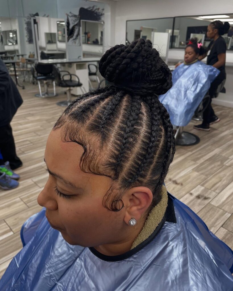 Cornrow braided bun hairstyle with neat braids gathered into a large top bun.