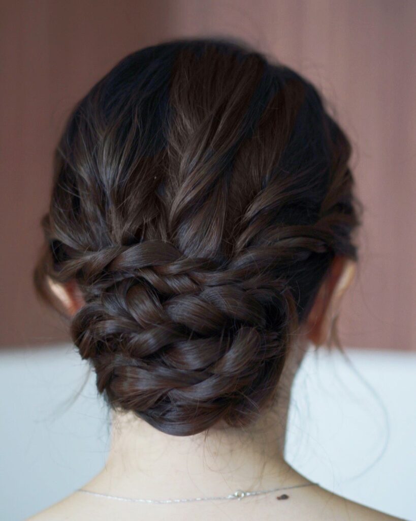 Soft low braided bun hairstyle with twisted sections and a relaxed textured finish.