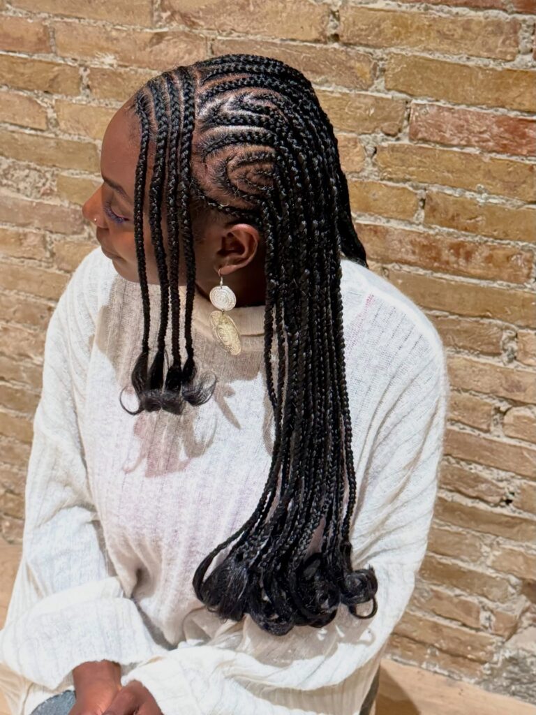 Fulani braids with swirl cornrows and long lengths finished with curled ends.