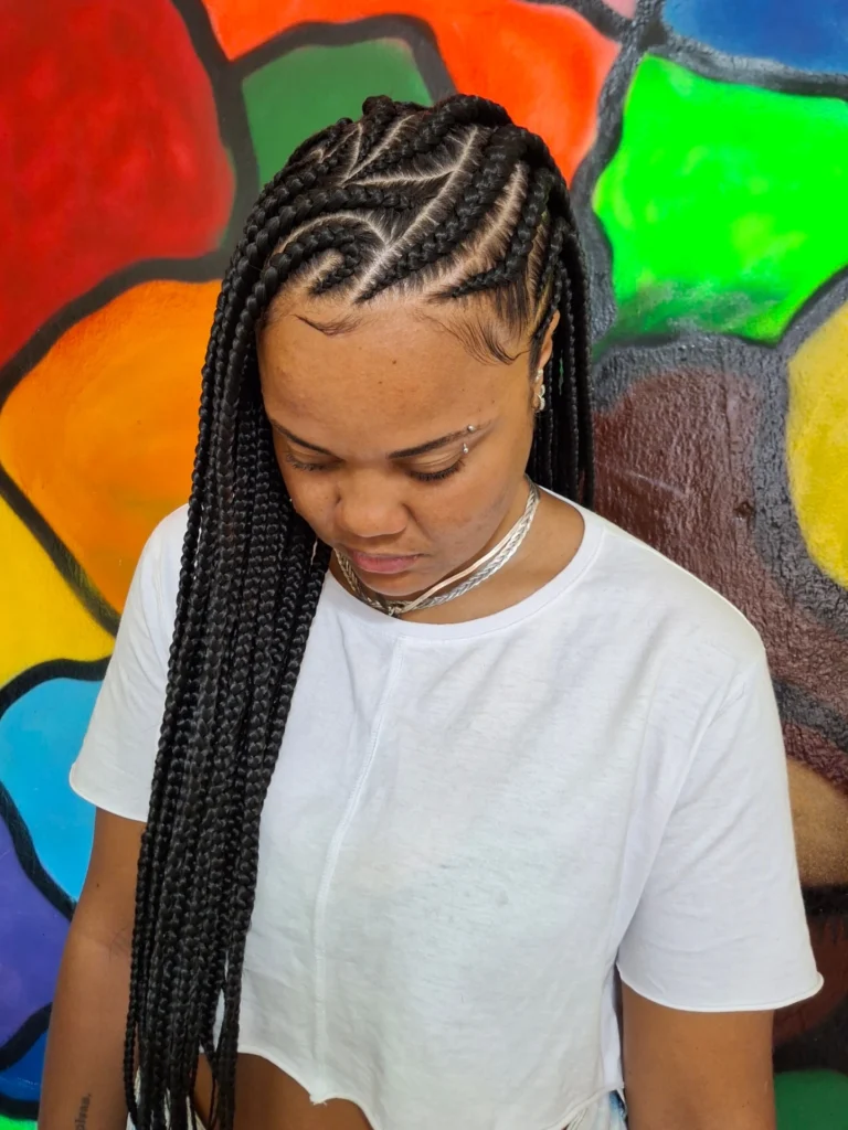 Fulani braids with curved cornrows and long lengths styled to one side.