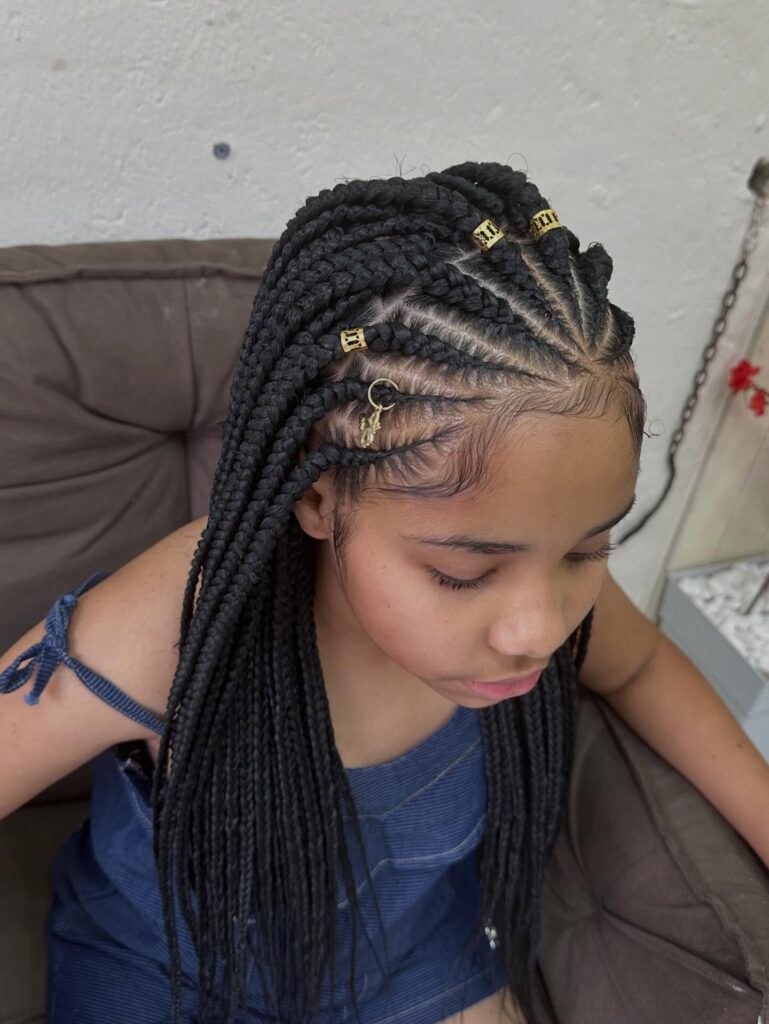 Fulani braids with curved cornrows and gold cuffs and charm accessories.