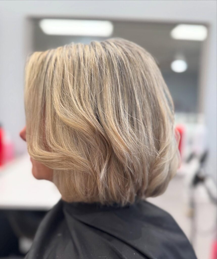A woman with a straight chin length bob in a creamy vanilla blonde shade.