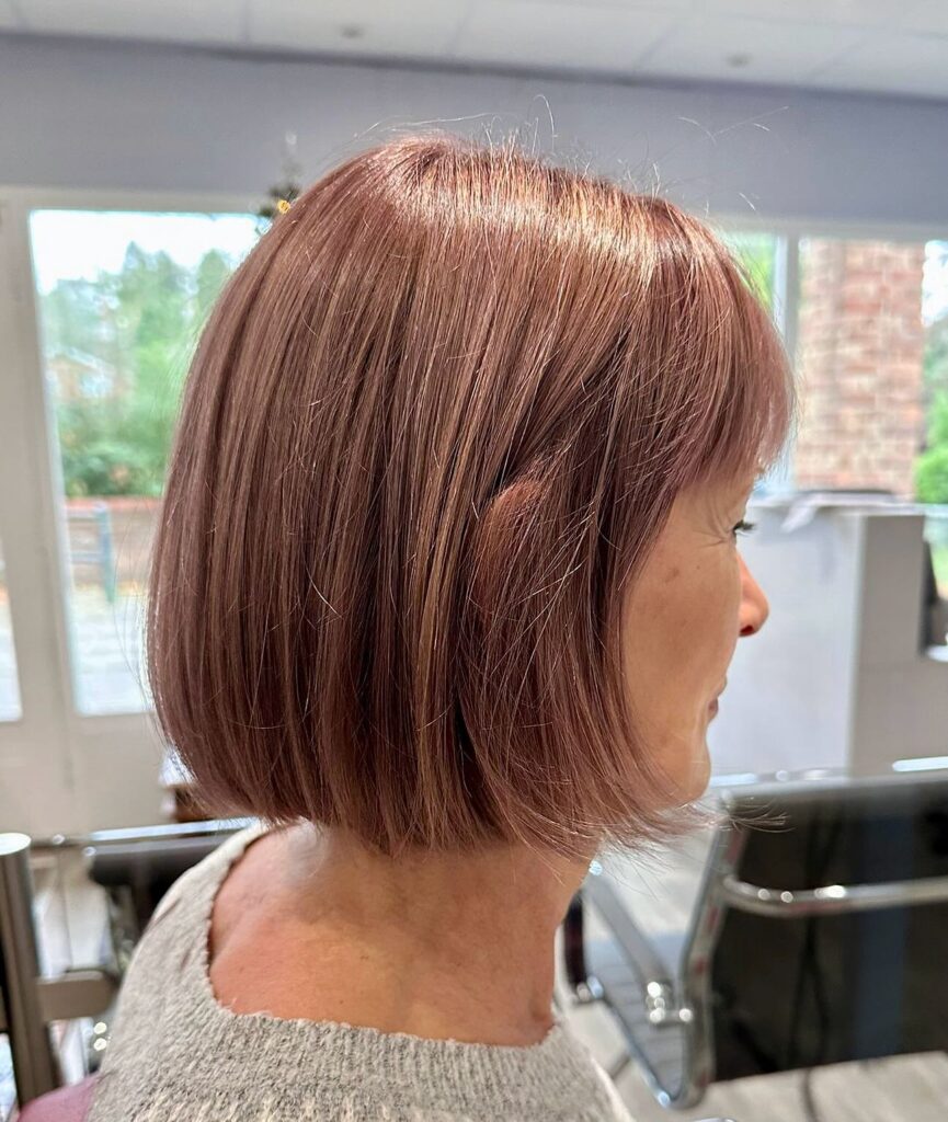A woman with straight shoulder length silver hair styled with a middle part and clean ends.