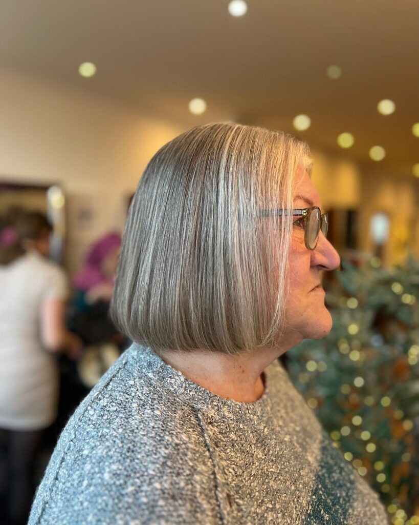 A woman with a sleek straight chin length bob in a cool ash blonde shade with subtle highlights.