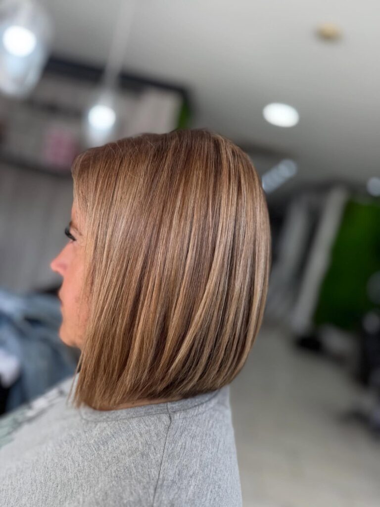 A woman with a straight shoulder length blunt bob in a sandy blonde shade with subtle fine highlights.