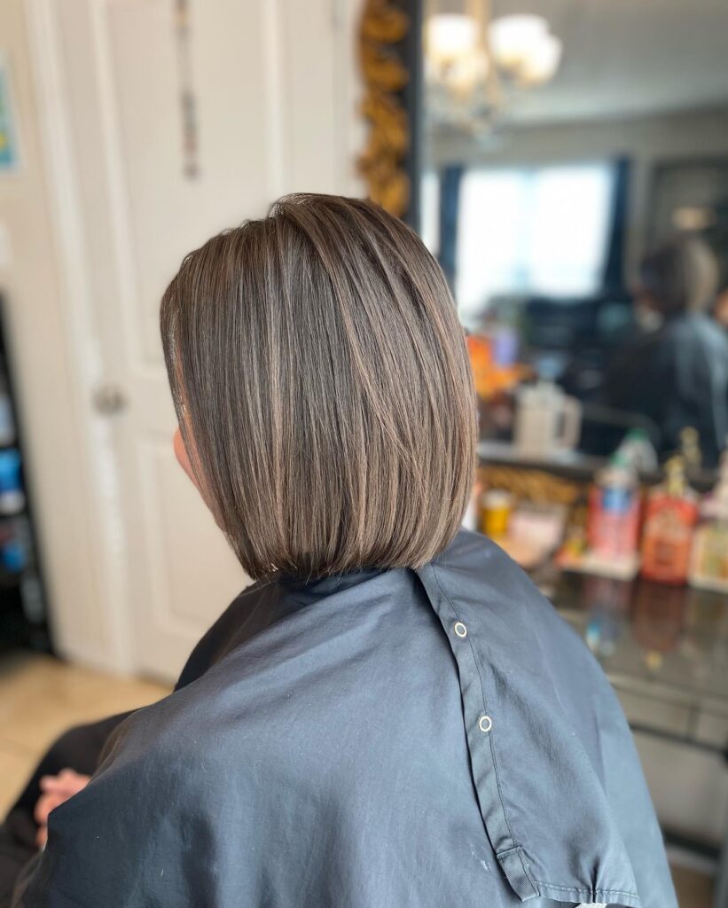 A woman with straight shoulder length blonde hair featuring long layers and a sunny luminous color.
