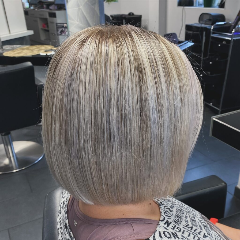 A woman with a short feathered white pixie cut featuring voluminous layers and a soft side swept fringe.