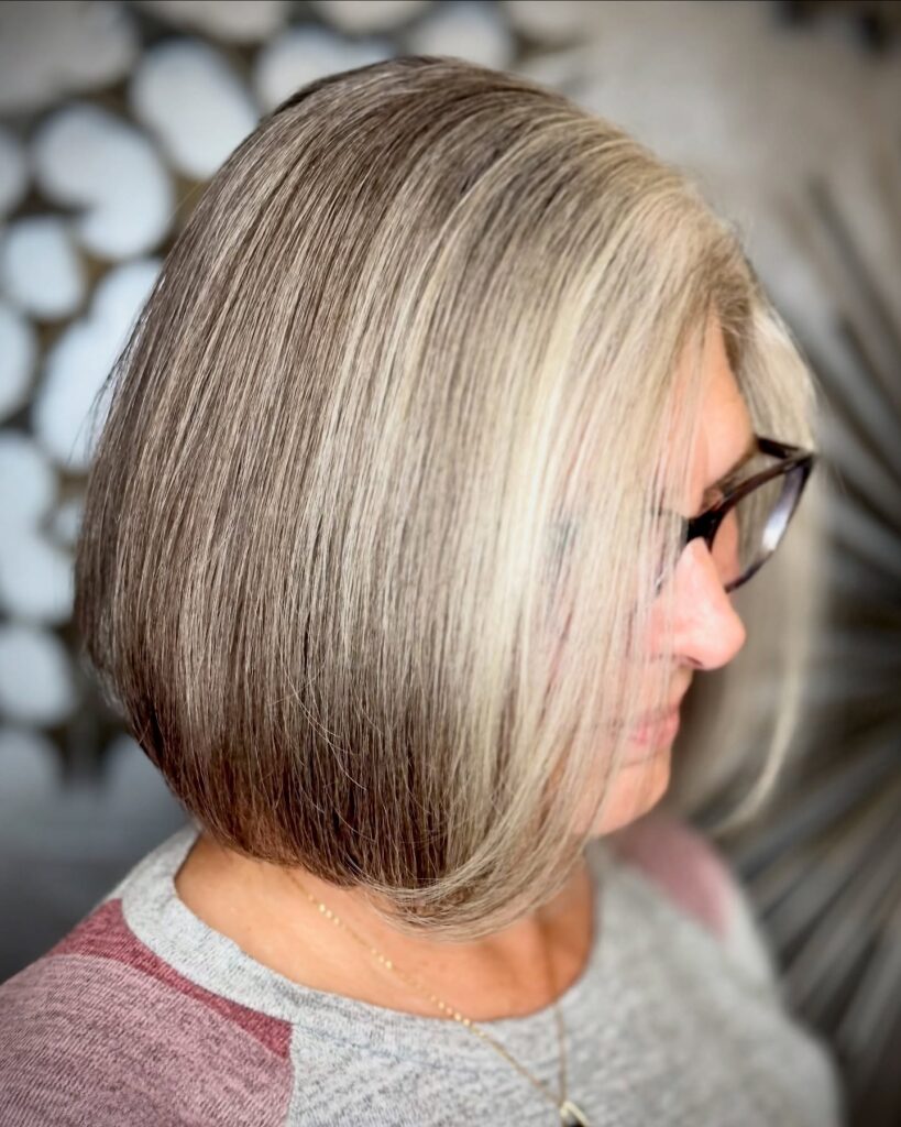 A woman with a square face shape wears a straight silver and grey A-line bob that curves toward her chin.