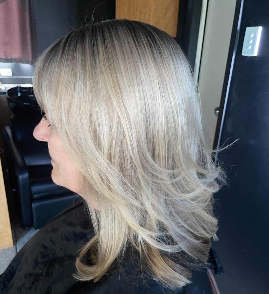 A woman with a round face features a textured silver pixie cut with short tapered sides and spiky layers on top.