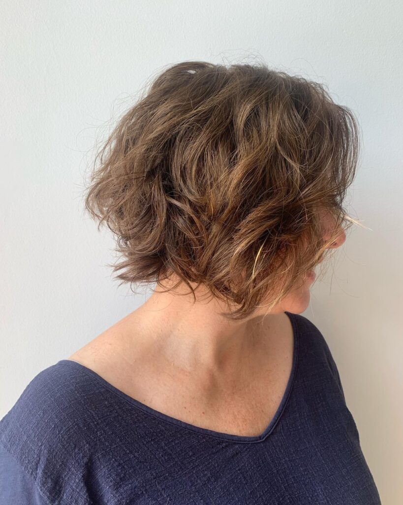 A woman with a short silver and grey pixie cut featuring a wavy textured top and tapered sides.