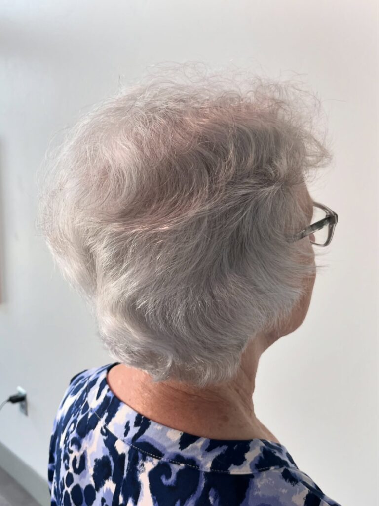 A woman with a short silver pixie cut styled with soft brushed back waves.