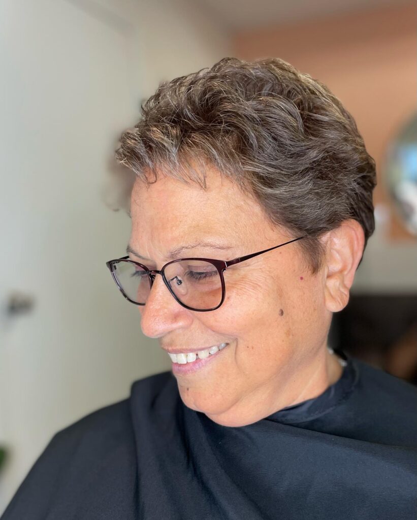 A woman with a shoulder length silver white shaggy cut featuring voluminous waves and charcoal lowlights.