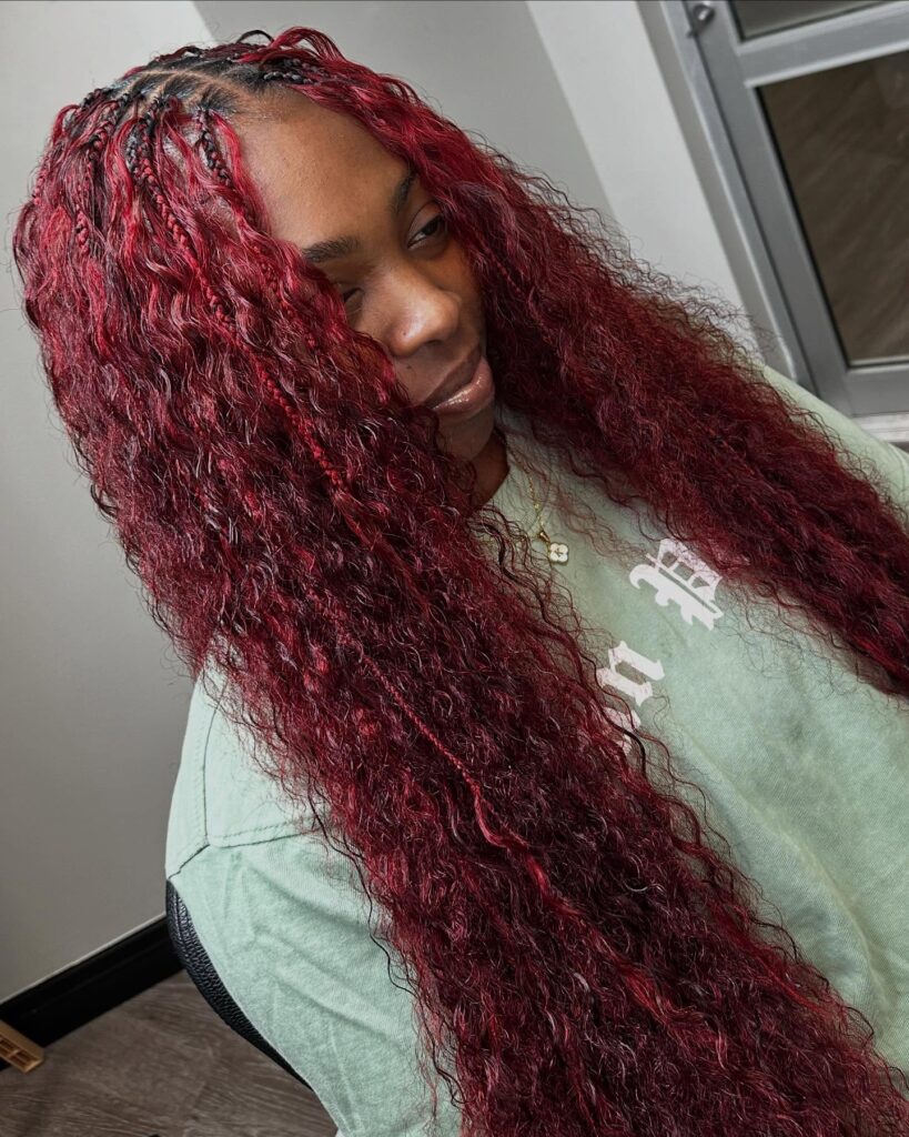 Long deep red boho braids mixed with loose wavy hair for a textured look.