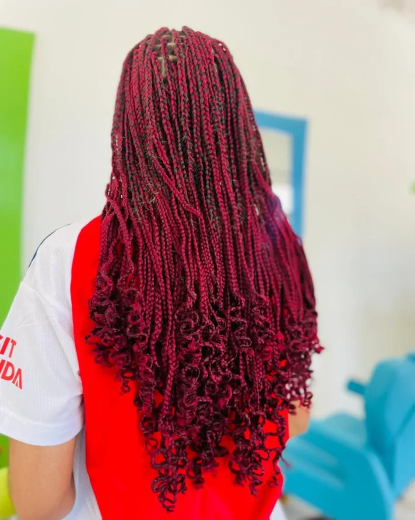 Red micro braids styled with curly ends for added volume and movement.