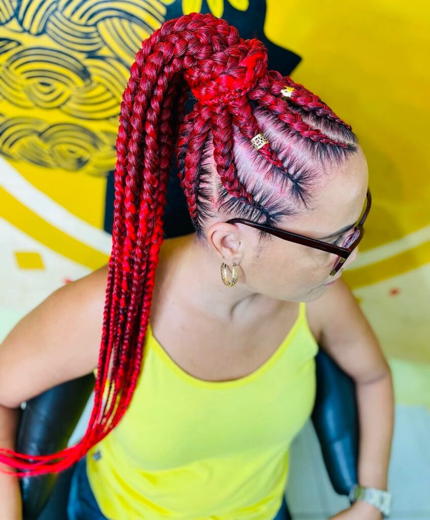 Long ombre red box braids with dark roots and bright red ends decorated with gold cuffs.