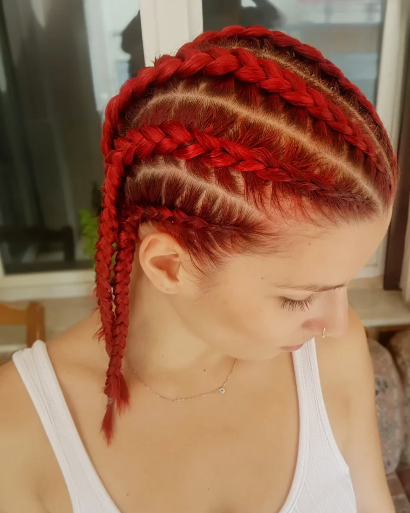 Bright red cornrows with a thick crown braid and a few braids hanging down.