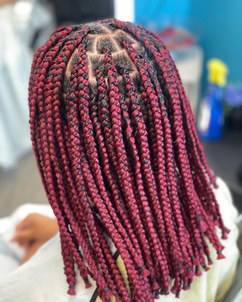 Medium box braids in a burgundy color with neat parts and uniform size.