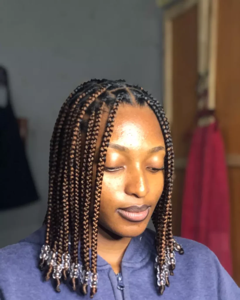 Short medium box braids with clear beads at the ends and a center part.