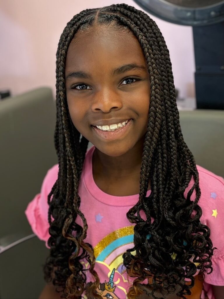 Medium box braids with a center part and soft curly ends on a child.