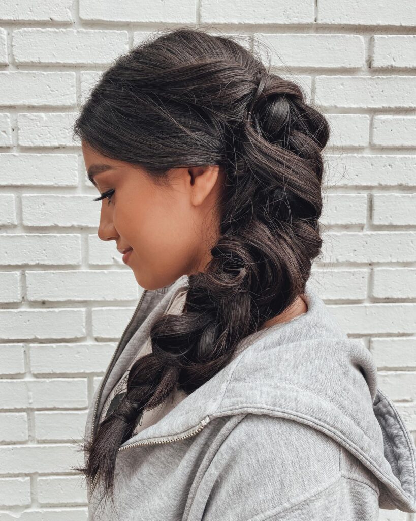 Thick side braid transitioning into a low twisted section on dark hair.
