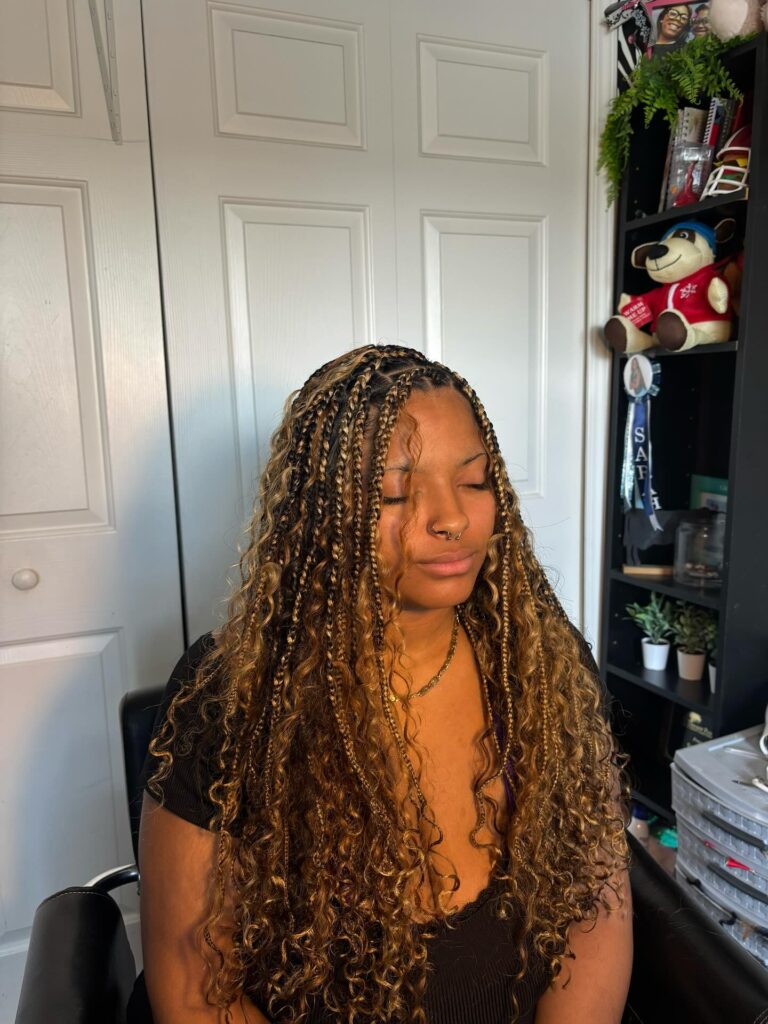 Honey blonde braids with curly ends creating a full and voluminous style.