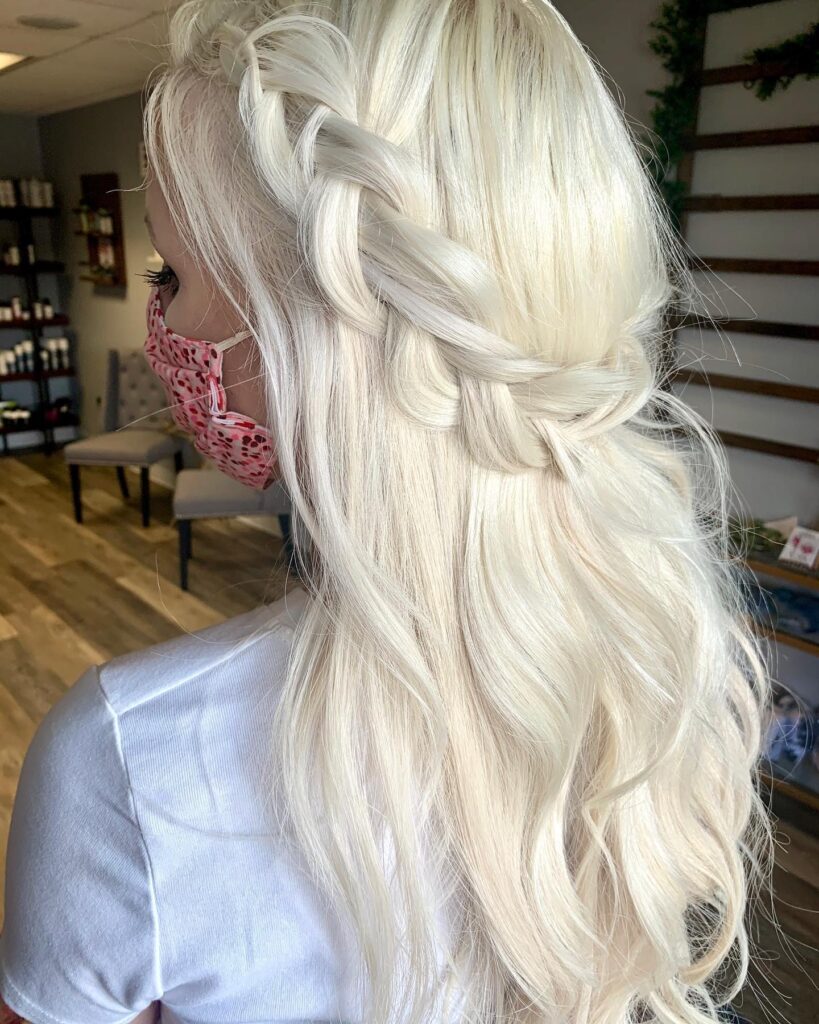 Platinum blonde hair styled in a loose waterfall braid with soft waves.