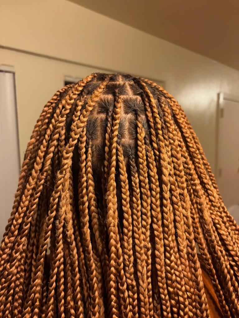 Medium length honey blonde box braids with neat parts and uniform braid size.