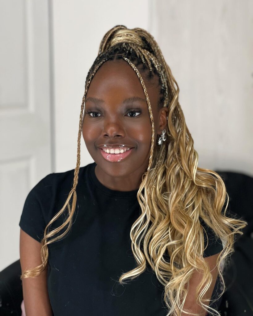 High ponytail with braided roots and long wavy blonde extensions with face-framing braids.