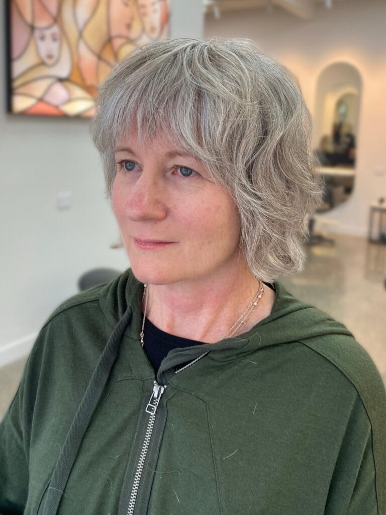 Short textured gray bob with feathered bangs and soft layers.