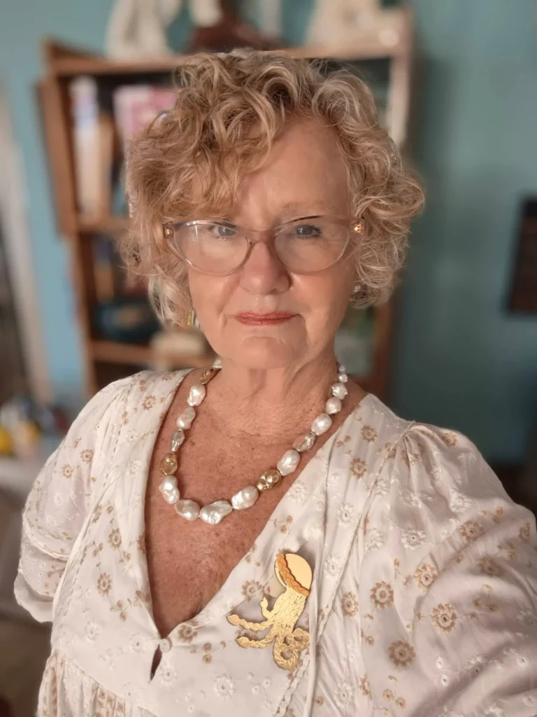 Short curly blonde hairstyle with soft bangs and natural volume.