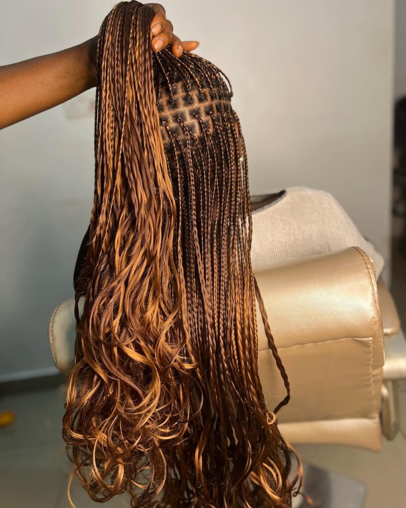 A back view of long caramel brown micro braids featuring neat square partings and loose wavy ends.