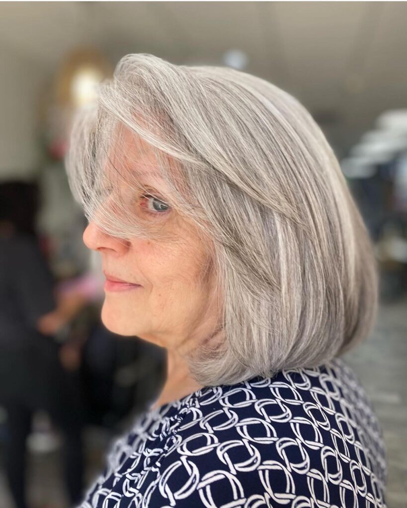 A woman with a rounded pearl gray long bob featuring sweeping side bangs and soft layered ends.
