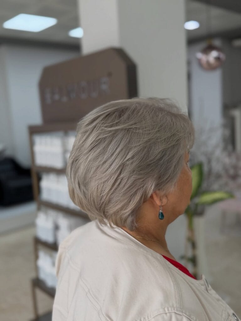 A side view of a woman with a soft ash blonde layered bob featuring a smooth rounded shape.