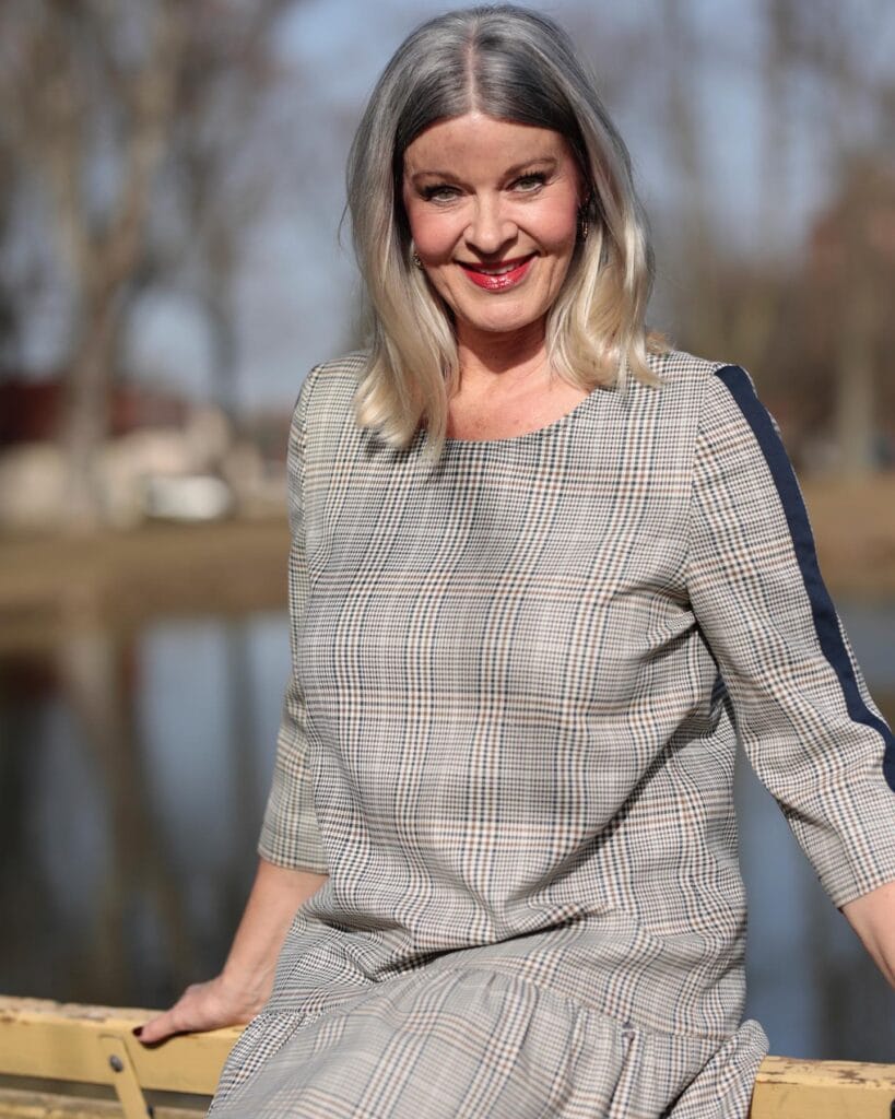 A woman with shoulder length silver and blonde hair styled in a straight lob with a center part.