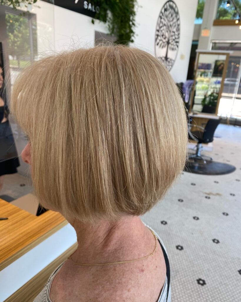 A side profile of a woman with a smooth and rounded honey blonde bob that curves inward at the chin.