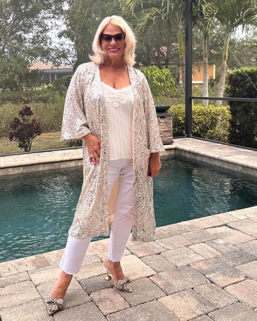 A woman with a shoulder length platinum blonde bob with flipped out ends standing by a pool.
