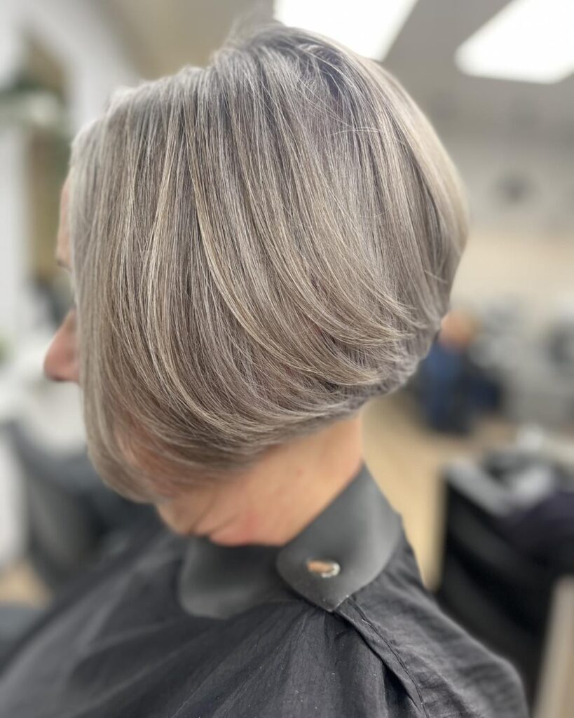 A side profile of a woman with a stacked silver wedge bob showing soft layers and natural gray tones.