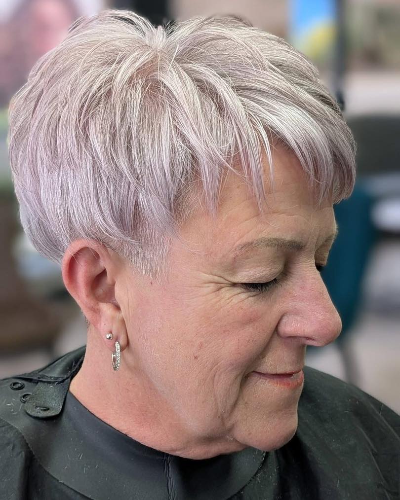 Short blonde feathered pixie haircut with soft lift and light texture.