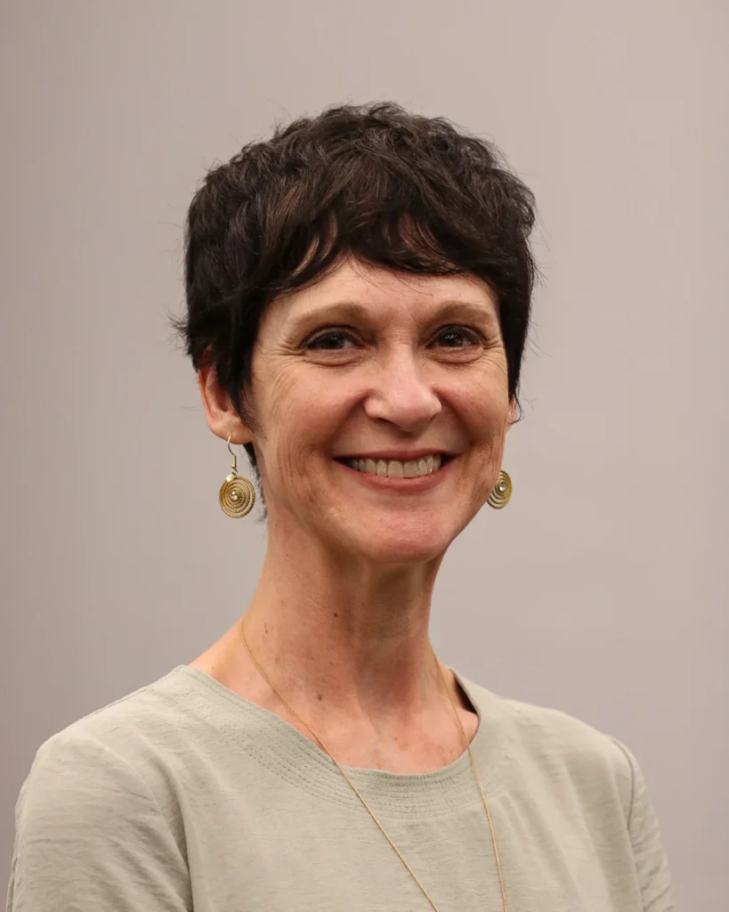 Short dark pixie haircut with a soft fringe and a rounded shape.