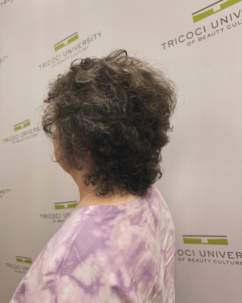 Short curly pixie haircut with a soft rounded shape and natural volume.