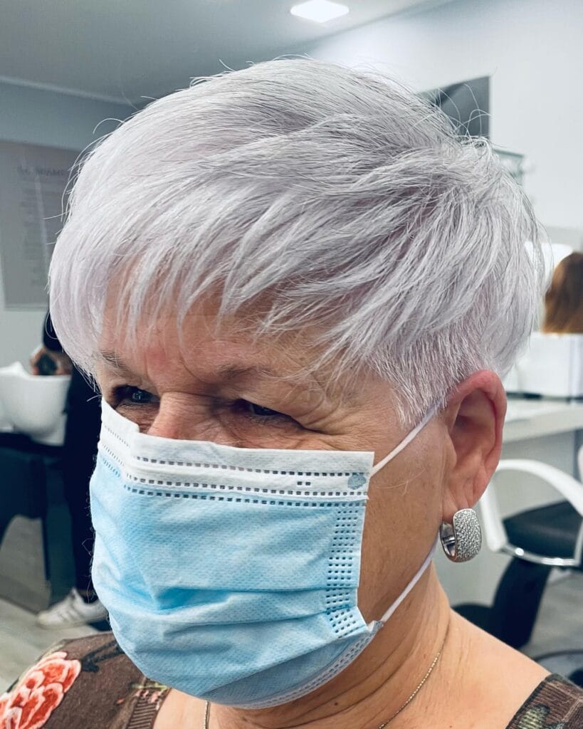 Short white pixie haircut with feathered layers and a soft fringe.