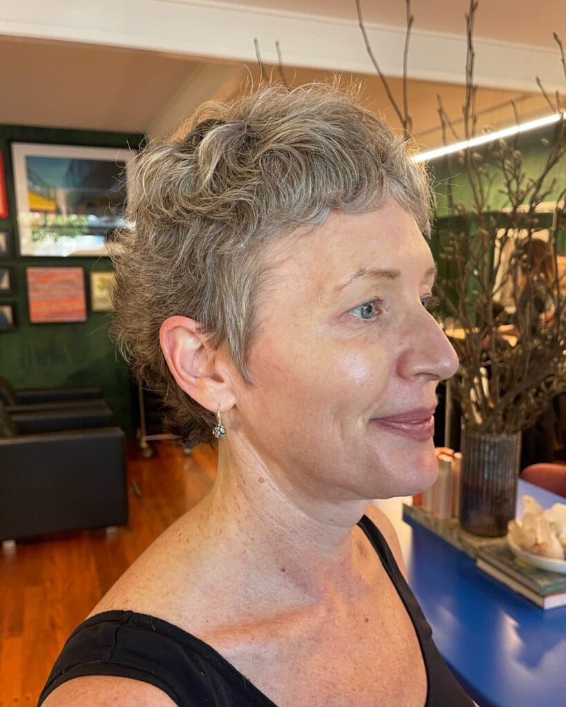 Short gray curly pixie haircut with natural volume and soft texture.